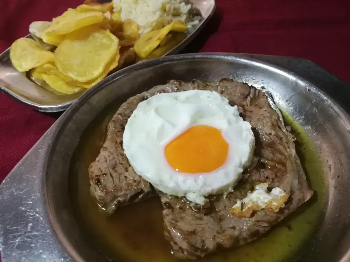 Bistecca in padella con uovo, riso e patatine